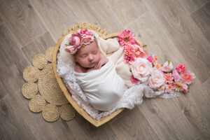 nouveau-ne dans un cœur en bois avec de belle fleur