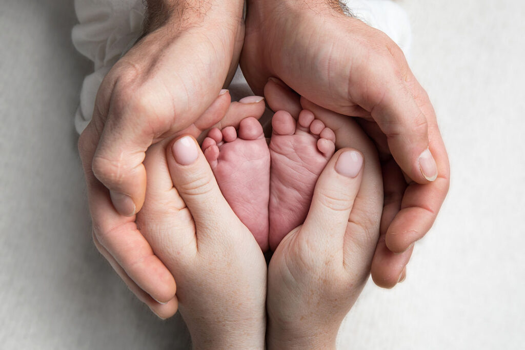 Mains tenant deux petits pieds de bébé rose pâle