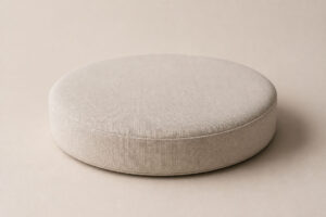 Pouf rond en tissu beige clair, idéal comme support essentiel pour les poses en photographie de nouveau-né.