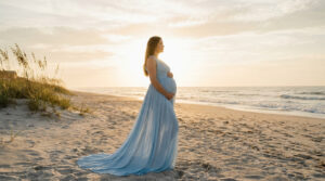 Femme enceinte en robe longue bleue sur une plage au coucher du soleil dans l'Hérault.