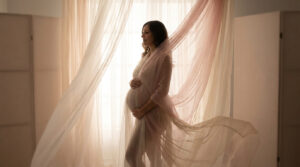 Sublimer votre silhouette avec le jeu des voilages en studio Femme enceinte posant de profil, drapée dans des voilages légers dans un studio baigné de lumière douce.